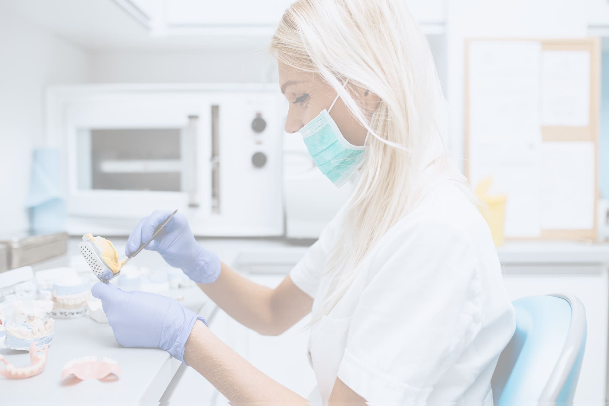 Eine Zahnärztin mit Maske und Handschuhen arbeitet sorgfältig an einem Zahnabdruck in einer hellen Praxis